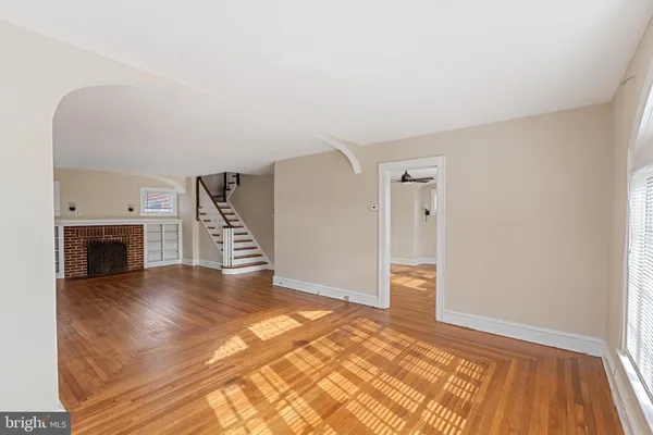 a view of an empty room with wooden floor fireplace and a window
