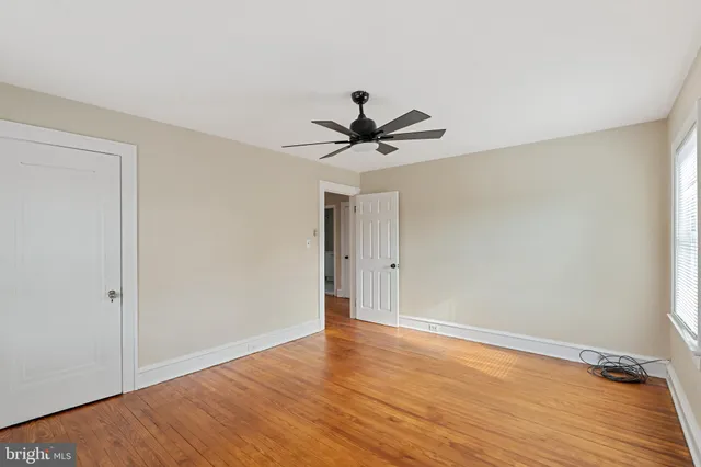 a view of room with wooden floor and a ceiling fan