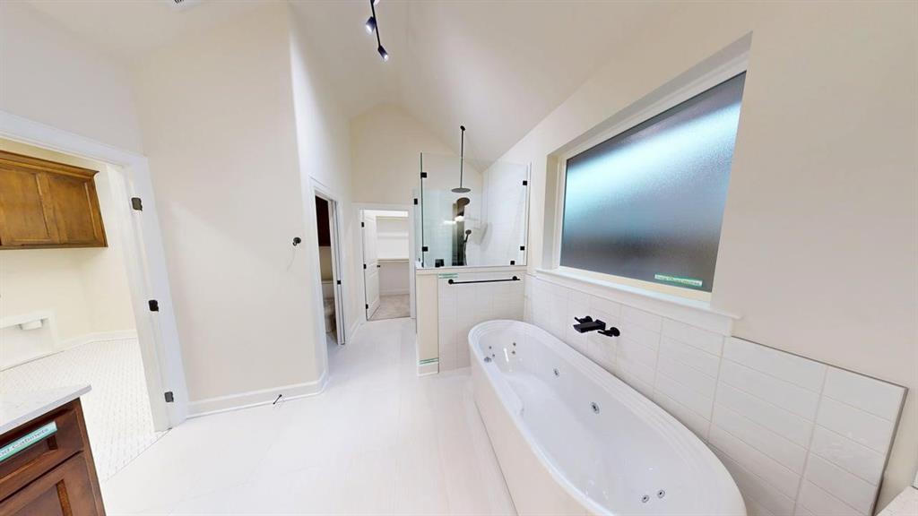 2509 Windmill Lane Longview, TX 75601 - Photo 8 of 35 Bathroom with a jetted tub, walk in shower, vaulted ceiling, vanity, and tile walls