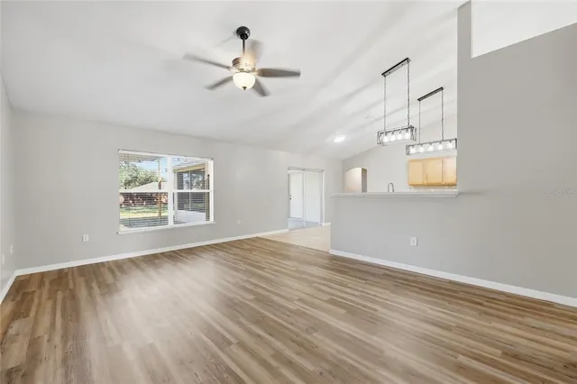 a view of an empty room with a window and wooden floor