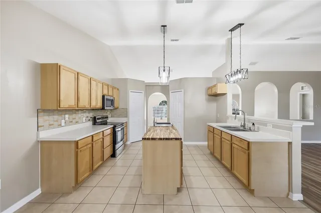 a large kitchen with kitchen island a stove a sink a center island and a refrigerator