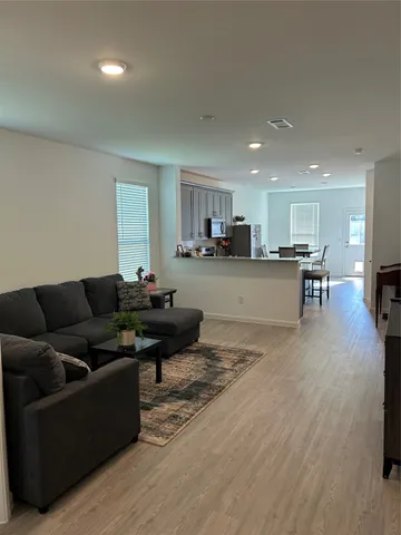 a living room with furniture and a dining table with kitchen view