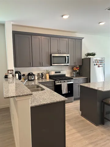 a kitchen with kitchen island granite countertop a sink counter top space appliances and cabinets