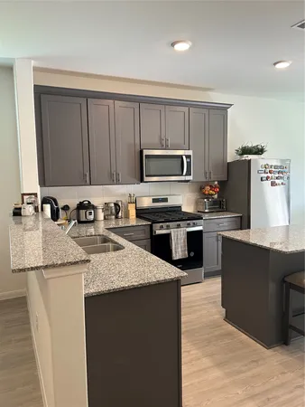 a kitchen with kitchen island granite countertop a sink dishwasher stove and microwave with wooden cabinets