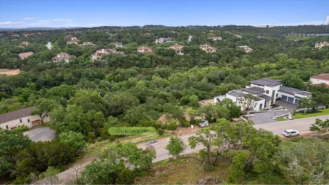 an aerial view of residential houses with outdoor space and trees