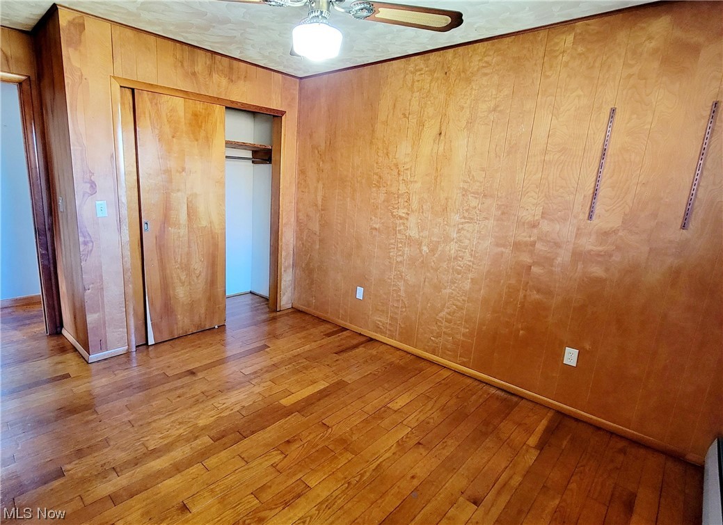 405 Bryan Road Milan, OH 44846 - Photo 15 of 35 Bedroom featuring ceiling fan, wood walls, a closet, and hardwood floors