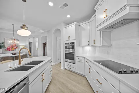 a kitchen with stainless steel appliances a sink a stove and cabinets