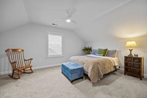 a spacious bedroom with a bed a chair and dresser