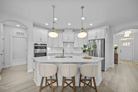 a kitchen with stainless steel appliances kitchen island wooden floor dining table and chairs