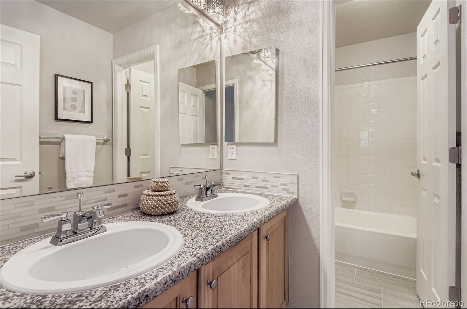 10726 Middlebury Way Highlands Ranch, CO 80126 - Photo 18 of 30 a bathroom with a granite countertop sink and a mirror a bathtub