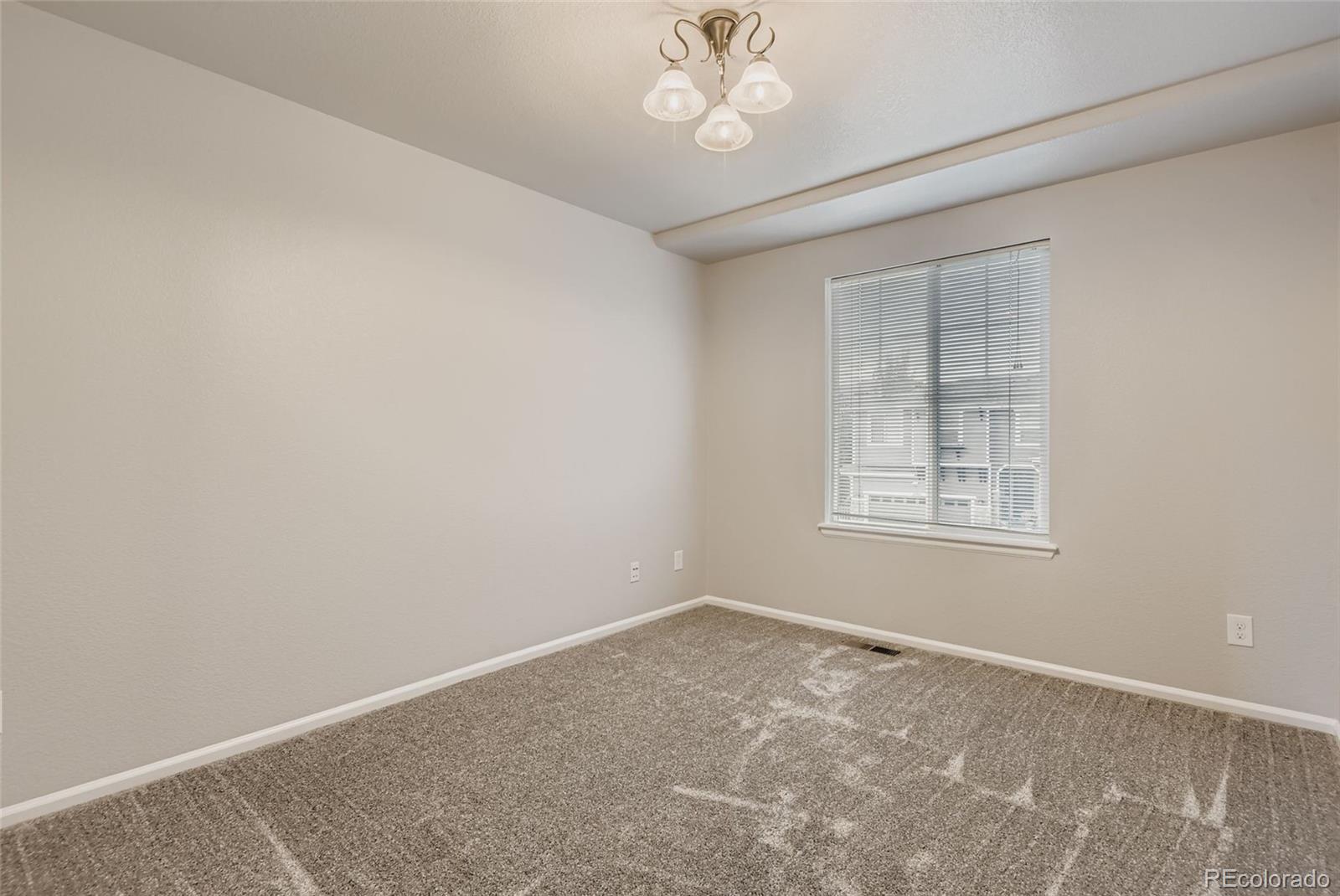 10726 Middlebury Way Highlands Ranch, CO 80126 - Photo 19 of 30 an empty room with a chandelier fan and windows