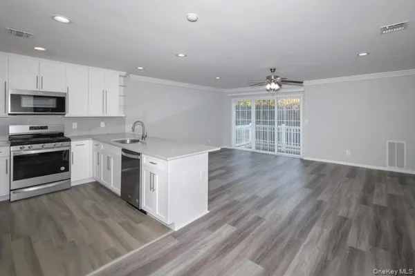 a kitchen with a sink wooden floor and stainless steel appliances