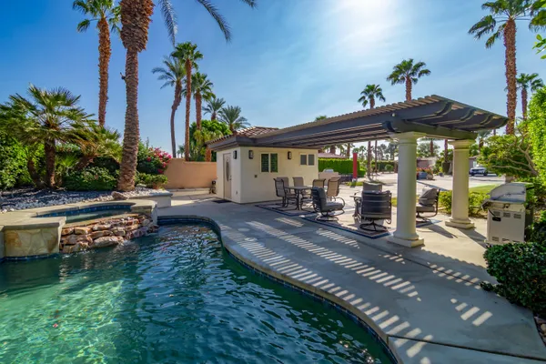 a backyard of a house with table and chairs under an umbrella