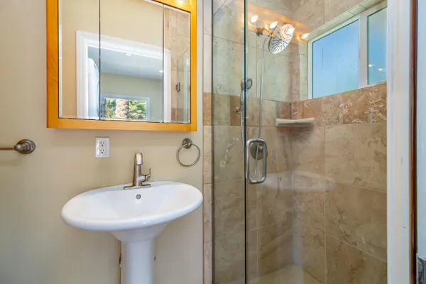 a bathroom with a sink shower and a mirror
