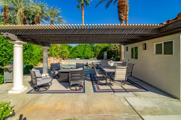 a view of patio with table and chairs under an umbrella with a barbeque
