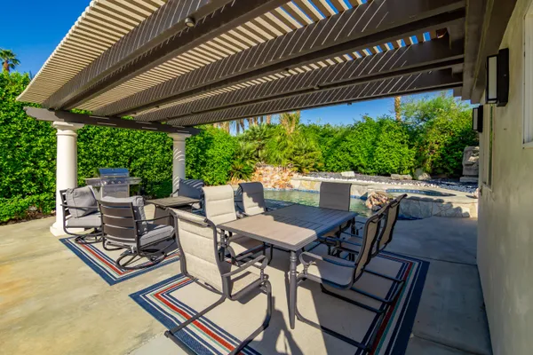 a view of a patio with table and chairs under an umbrella with a small yard
