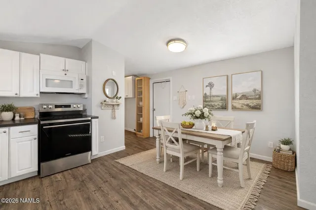 a kitchen with granite countertop stainless steel appliances a dining table and chairs