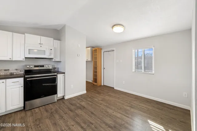 a kitchen with granite countertop a stove cabinets and wooden floor