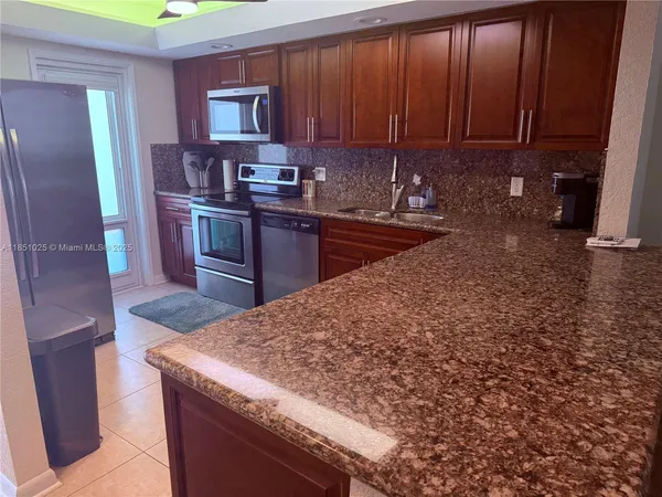 a kitchen with granite countertop a refrigerator stove and sink