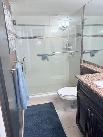a bathroom with a granite countertop sink toilet and shower