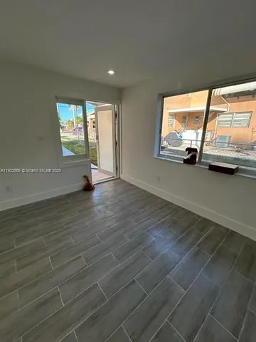 an empty room with wooden floor cabinet and windows
