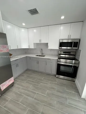 a view of a kitchen with wooden floor and electronic appliances