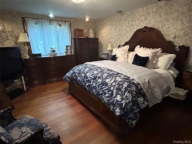 a bedroom with a bed dresser and window