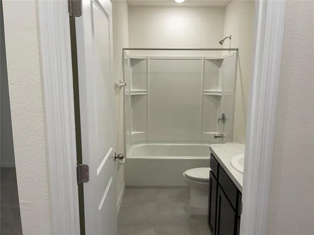 a bathroom with a granite countertop bathtub shower sink and toilet