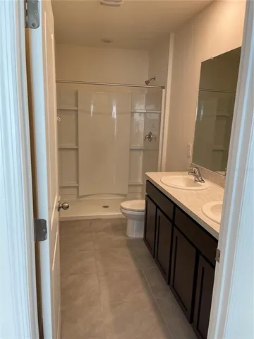 a bathroom with a double vanity sink toilet mirror and shower