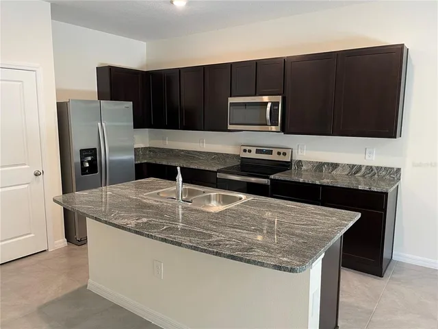 a kitchen with kitchen island granite countertop a stove and a microwave