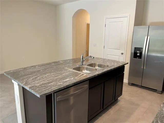 a kitchen with a granite countertop sink a refrigerator and cabinets
