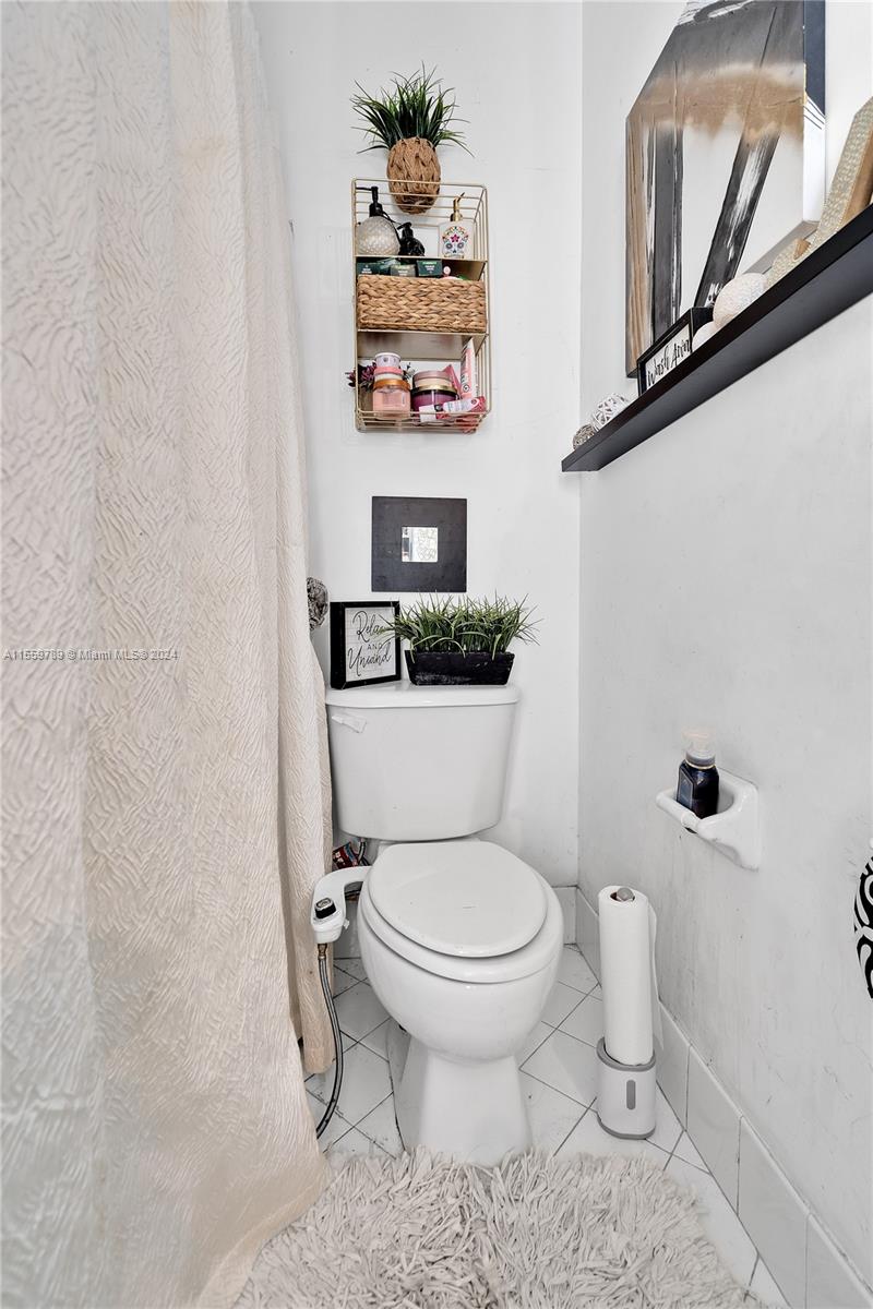 22438 Southwest 94th Path Cutler Bay, FL 33190 - Photo 21 of 38 a white toilet sitting next to a shower curtain
