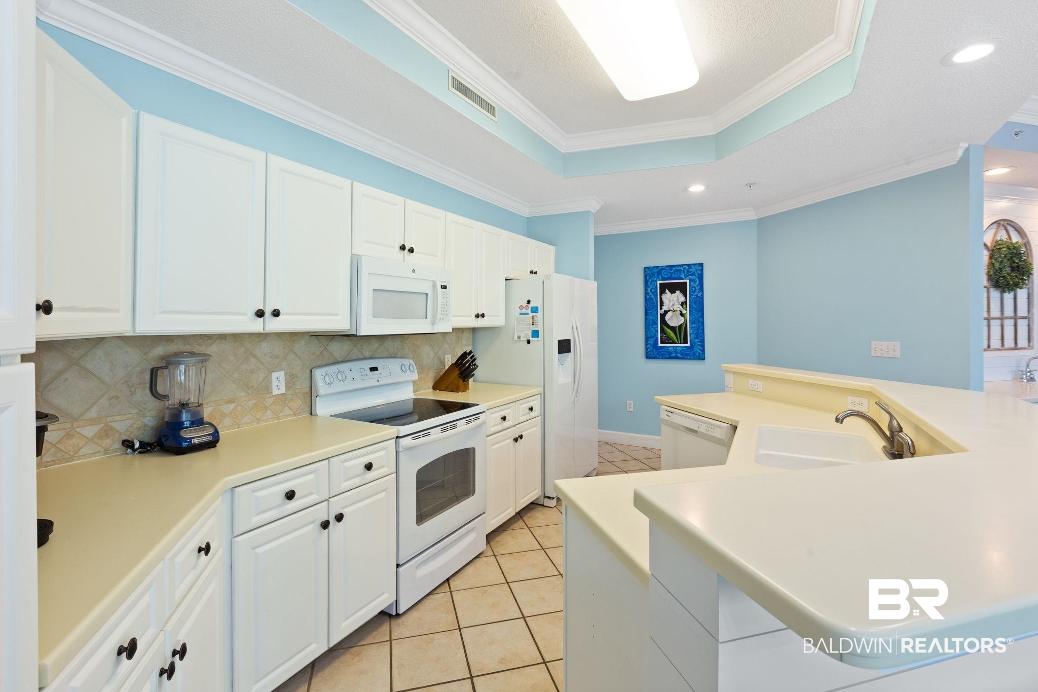 27580 Canal Road, Unit 1112 Orange Beach, AL 36561 - Photo 10 of 50 Kitchen with an island with sink, a tray ceiling, white appliances, white cabinetry, and recessed lighting