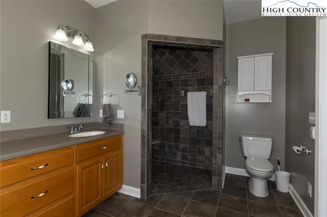 a bathroom with a granite countertop sink a toilet a mirror and shower
