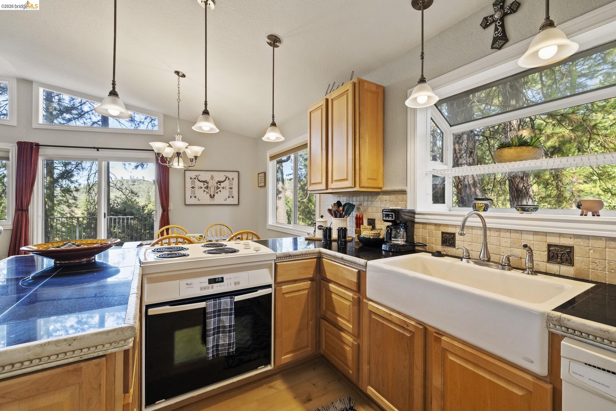 19369 Ferretti Road Groveland, CA 95321 - Photo 14 of 45 Kitchen featuring backsplash, white appliances, vaulted ceiling, light wood-type flooring, and tile countertops