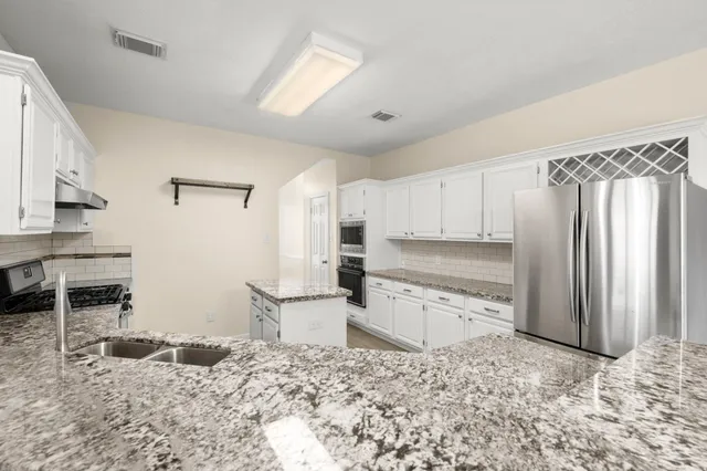 a view of a kitchen with stainless steel appliances granite countertop a stove a sink and a granite counter tops
