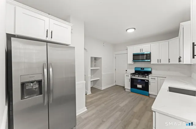 a kitchen with a refrigerator a stove top oven and cabinets