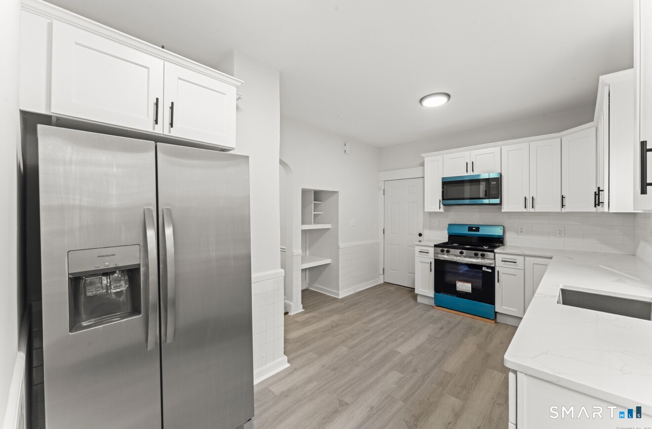 a kitchen with a refrigerator a stove top oven and cabinets