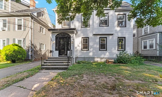 a view of a house with brick walls plants and large tree