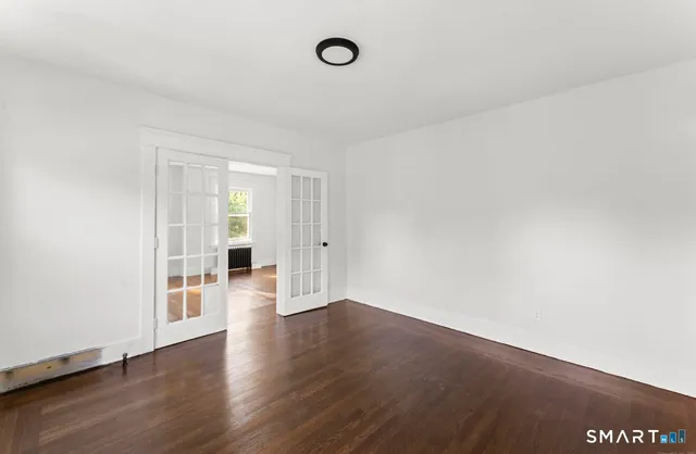 a view of an empty room with wooden floor and a window