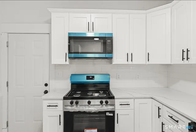 a kitchen with stainless steel appliances granite countertop white cabinets a stove top oven