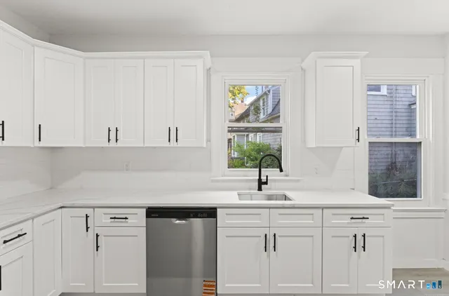 a kitchen with white cabinets and a window