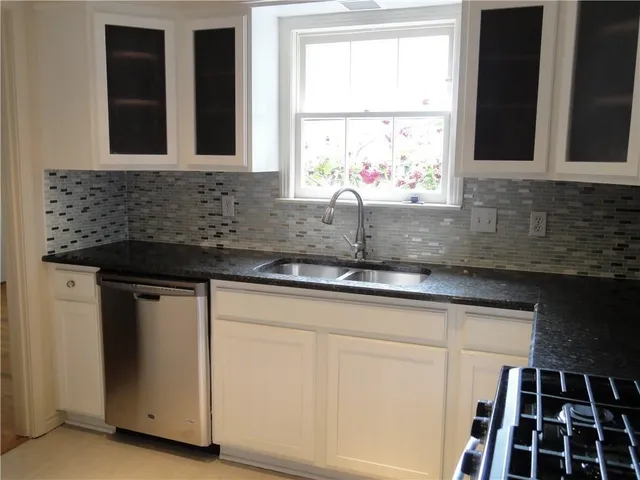 a kitchen with granite countertop white cabinets and sink