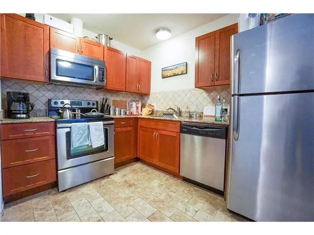 a kitchen with stainless steel appliances granite countertop a refrigerator a stove a sink and a microwave
