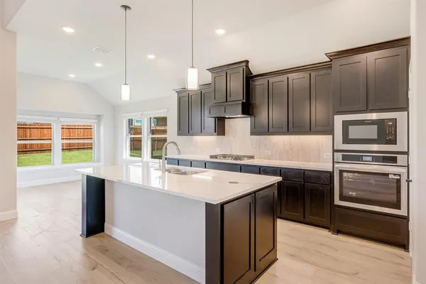 a kitchen with stainless steel appliances kitchen island granite countertop a sink refrigerator and cabinets