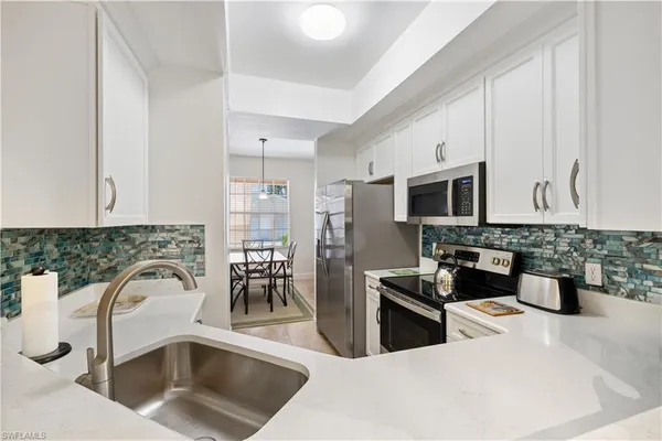 a kitchen with stainless steel appliances a sink a stove top oven a chimney and cabinets