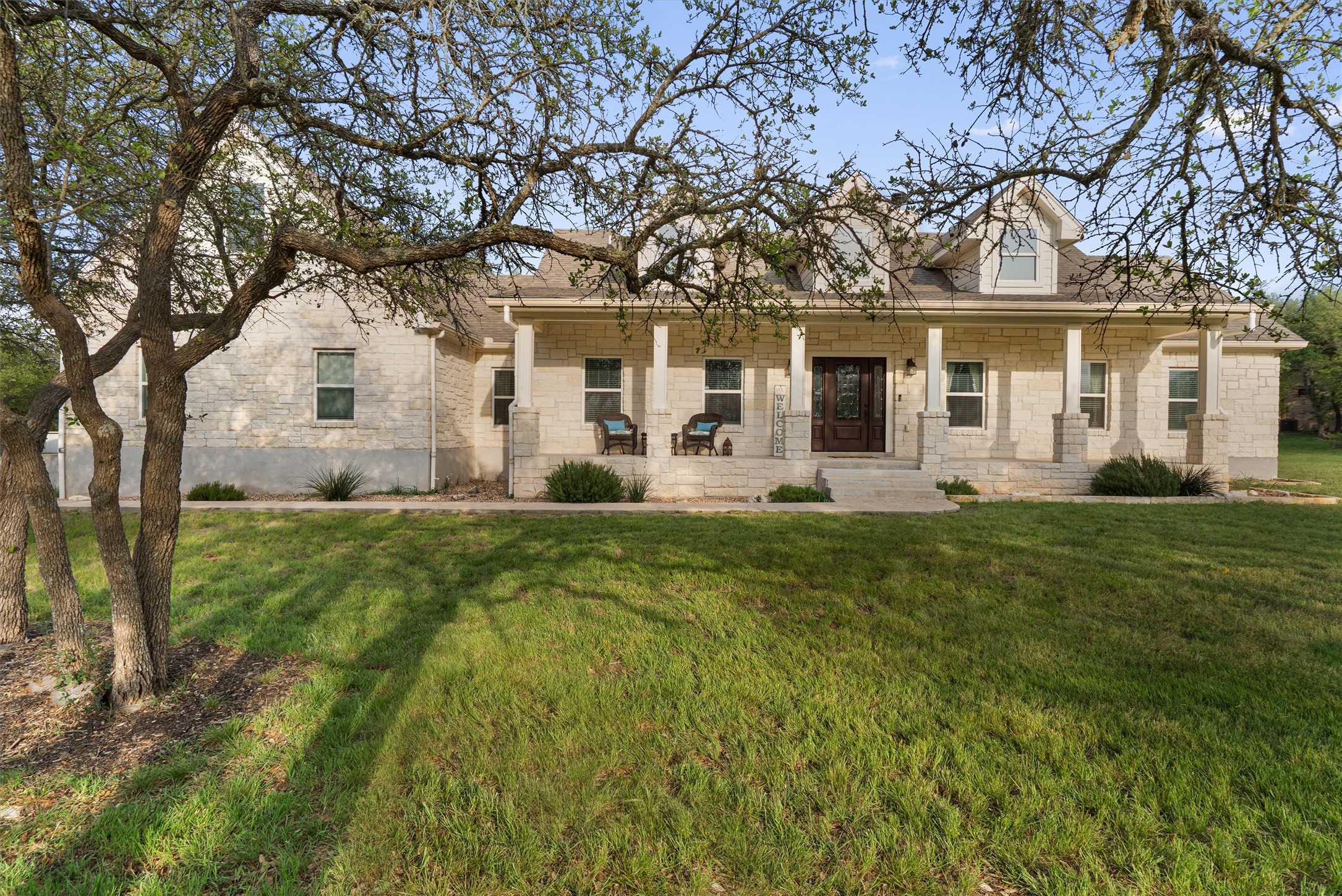 13105 Rooster Springs Road Austin, TX 78737 - Photo 1 of 38 The property features a stone exterior, a covered porch with stone columns, and a front entry with a dark wood door