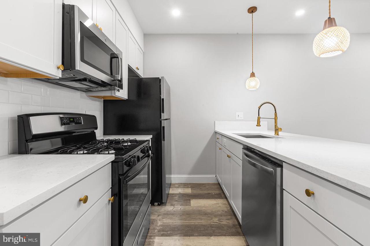 5706 Chestnut Street, Unit 2 Philadelphia, PA 19139 - Photo 5 of 8 a kitchen with stainless steel appliances granite countertop a stove and a sink