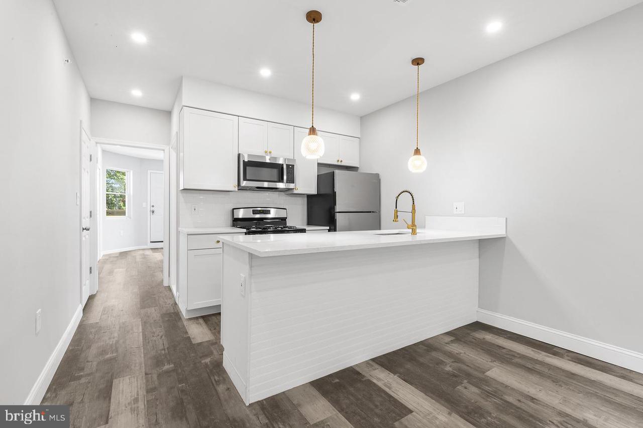 5706 Chestnut Street, Unit 2 Philadelphia, PA 19139 - Photo 7 of 8 a kitchen with kitchen island a sink stainless steel appliances and cabinets