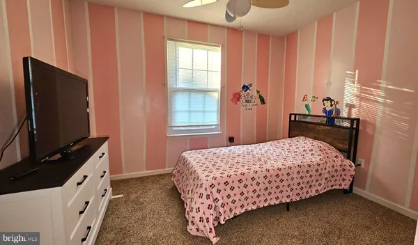 a bedroom with a bed and a flat tv screen on dresser